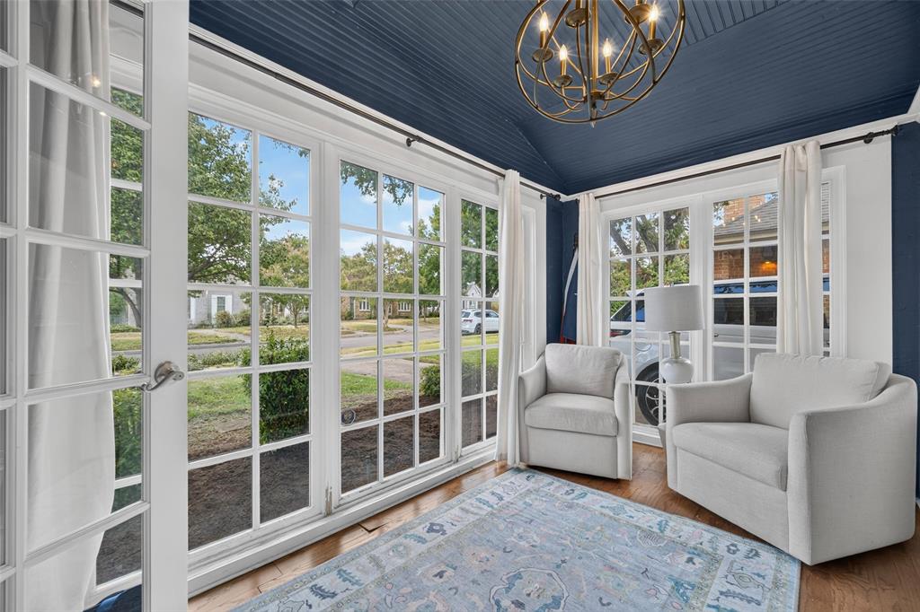 Wood-finish flooring, multiple paneled windows, vaulted ceiling, and an ornate chandelier