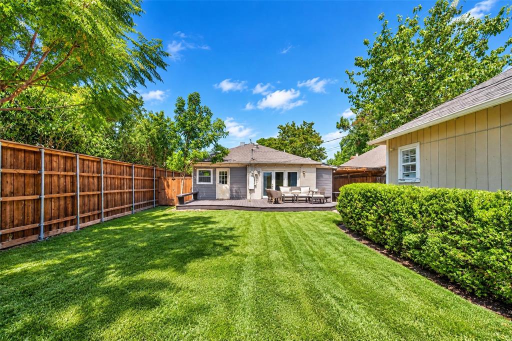 Expansive backyard featuring a manicured lawn, wood privacy fencing, and mature trees