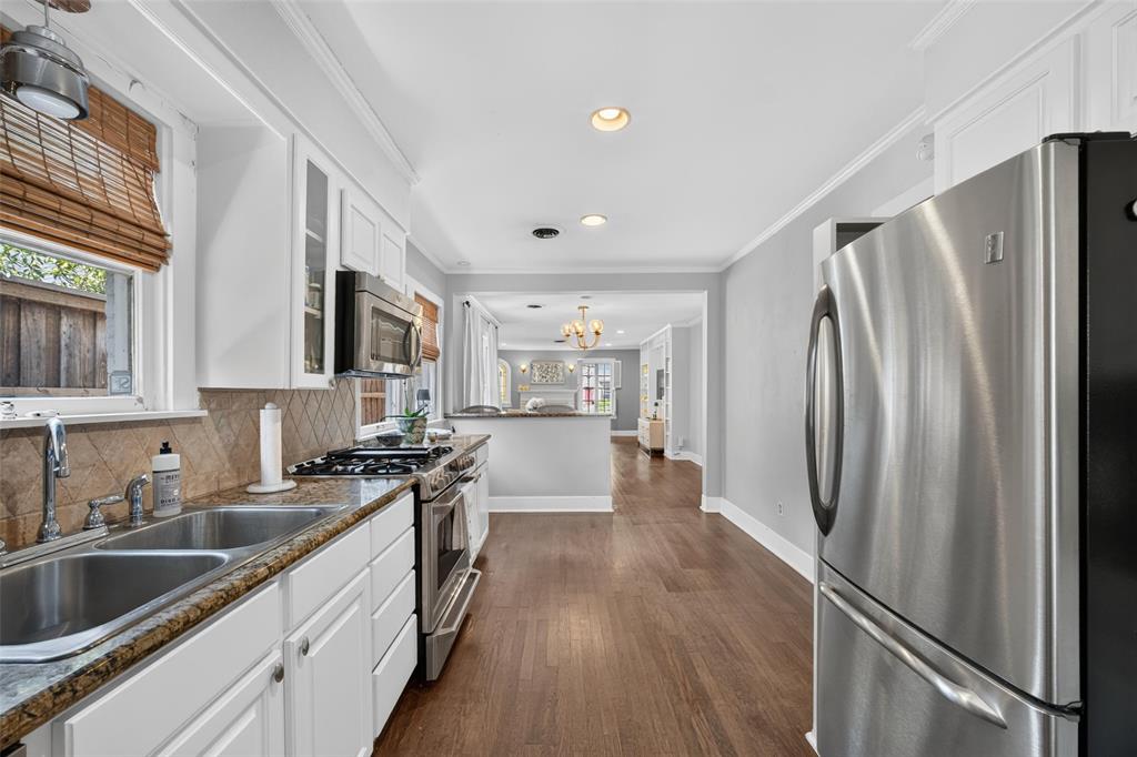 Stainless steel appliances, wood-finish flooring, white cabinetry, integrated double basin sink, and recessed lighting