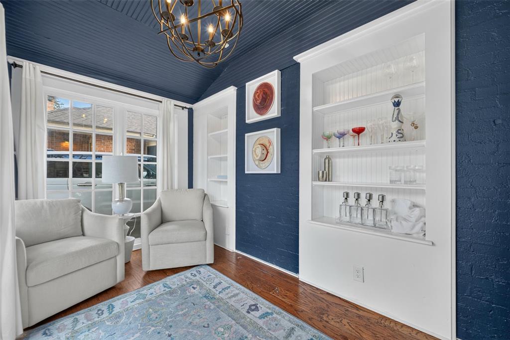 Hardwood flooring, built-in shelving, ornate chandelier, window with grid panes, textured wall finish
