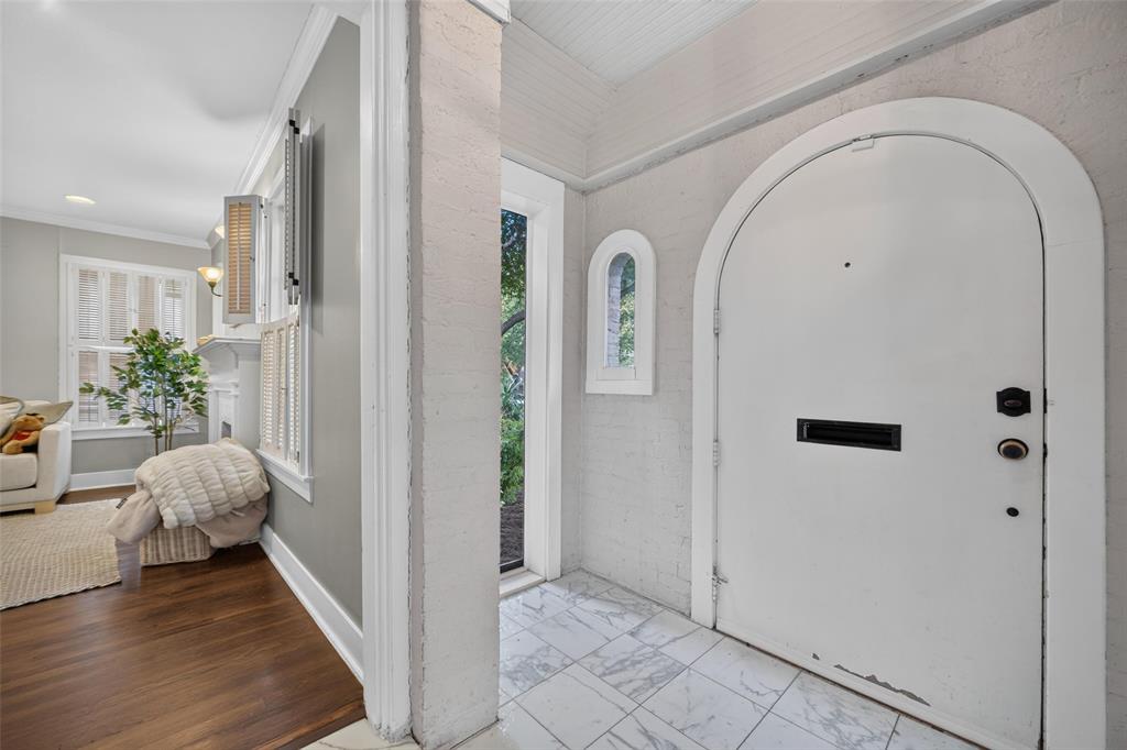 Arched entry door with black hardware, white tile flooring, and an arched window