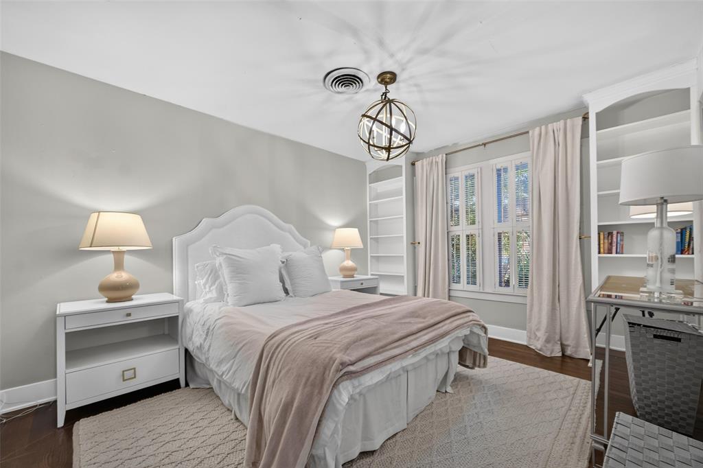 Hardwood flooring, built-in shelving, white window shutters, and a decorative ceiling light fixture