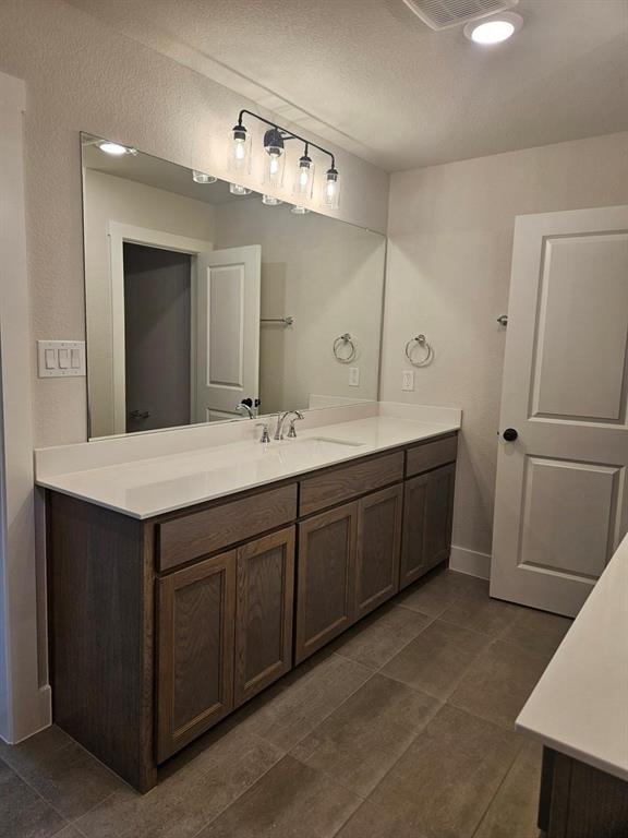 Double vanity with light wood-finish cabinetry and white countertops
