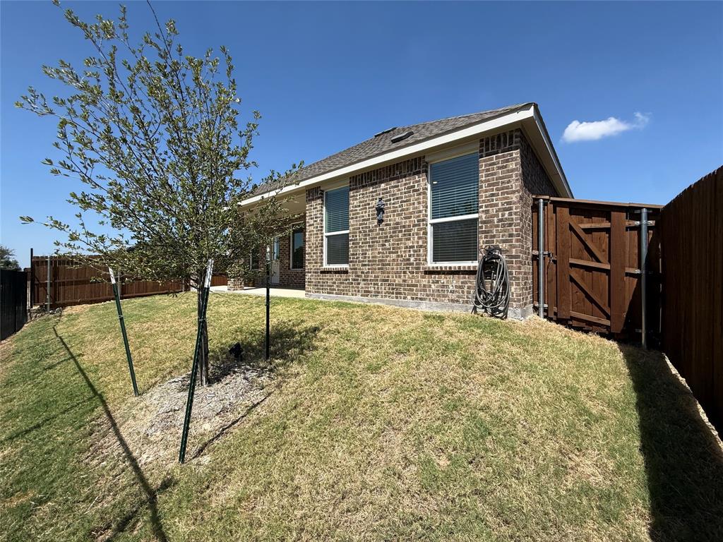 Brick exterior featuring a hip roof, privacy fencing, and a side gate