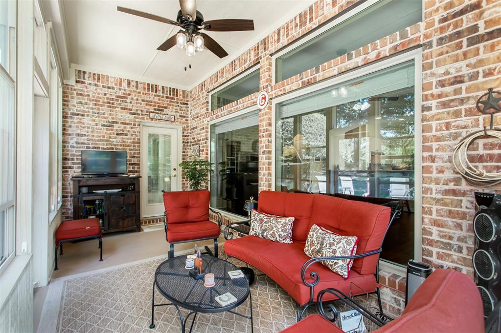 Enclosed sunroom featuring brick accent walls, ceiling fan, and multiple large windows