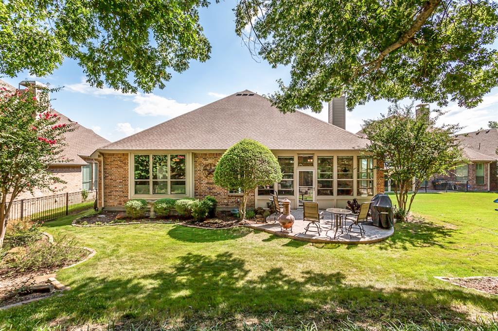Expansive backyard with a manicured lawn, brick exterior, and a built-in patio
