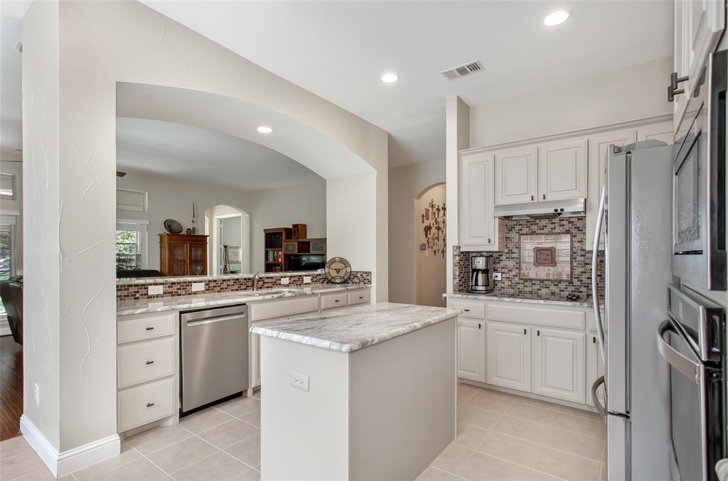 Kitchen featuring white cabinetry, light-toned countertops, a mosaic tile backsplash, stainless steel appliances, and recessed lighting