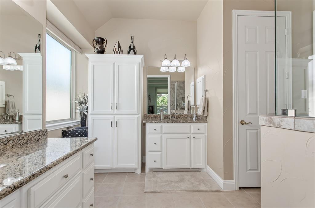 Dual vanity with granite countertops, white cabinetry, a built-in storage cabinet, and a tiled floor