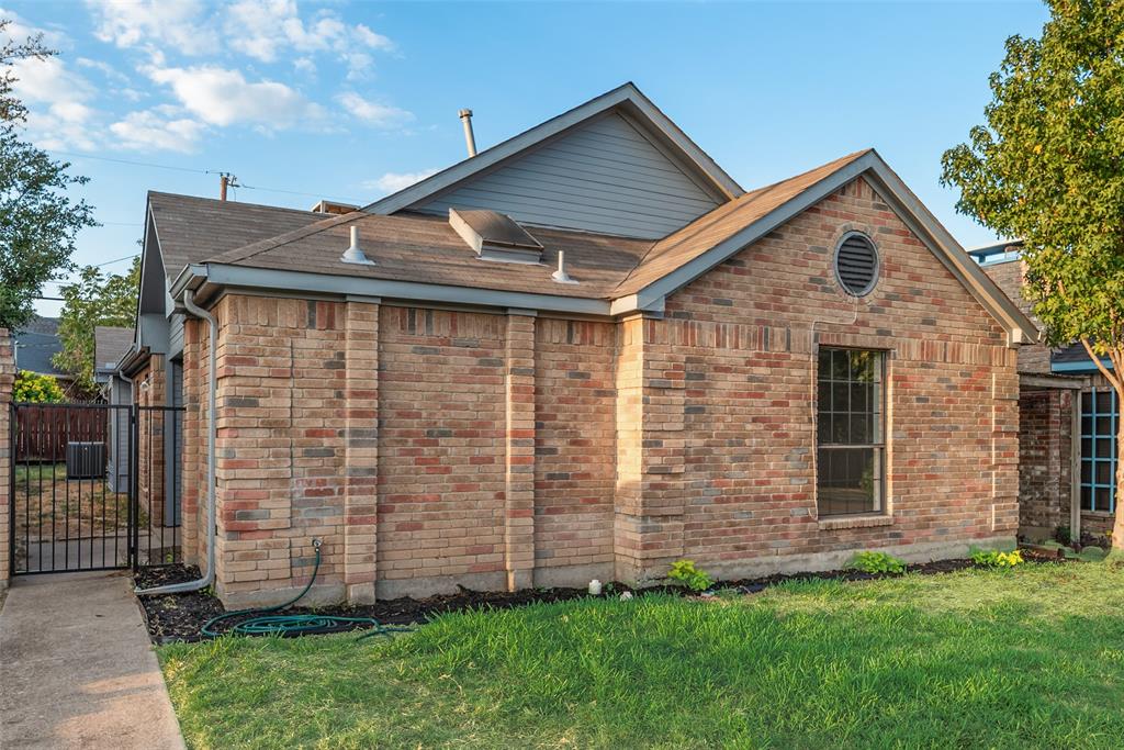 Brick exterior with an ornamental circular vent, a prominent window, a metal gate, and partial yard space Brick exterior with an ornamental circular vent, a prominent window, a metal gate, and partial yard space
