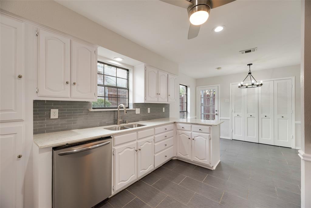 Kitchen featuring white cabinetry, light-toned countertops, a tile backsplash, stainless steel dishwasher, and tiled flooring Kitchen featuring white cabinetry, light-toned countertops, a tile backsplash, stainless steel dishwasher, and tiled flooring