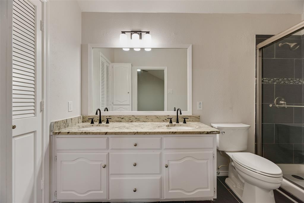 Dual vanity with granite countertop, white cabinetry, and matte black fixtures