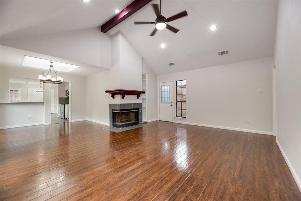 Vaulted ceiling with exposed beam, wood-finish flooring, recessed lighting, ceiling fan, and a tiled fireplace with wood mantel Vaulted ceiling with exposed beam, wood-finish flooring, recessed lighting, ceiling fan, and a tiled fireplace with wood mantel