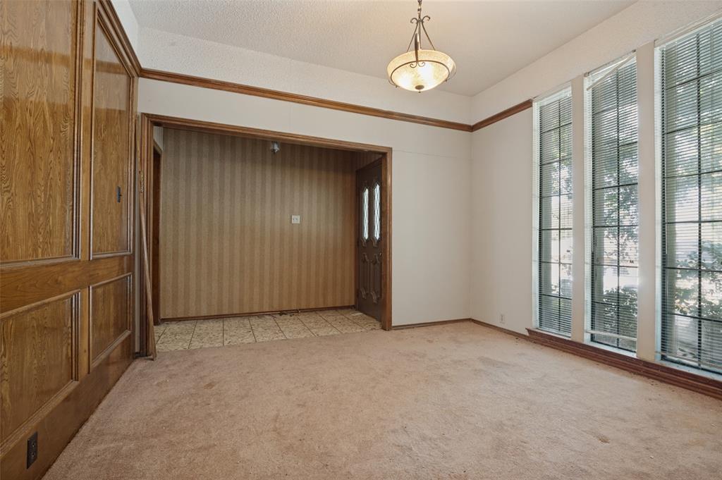 Wood-paneled wall, recessed entry, full-light entry door with sidelights, three tall windows with blinds, and a traditional ceiling fixture