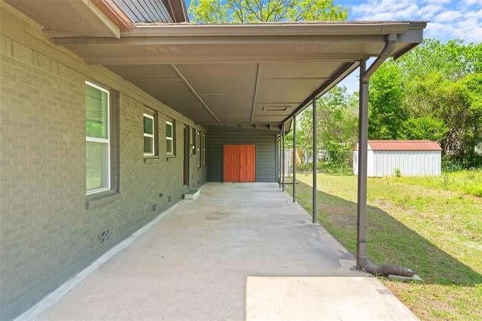 Expansive covered patio with concrete flooring, supported by metal columns