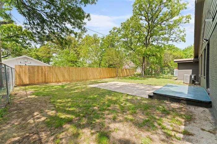 Expansive backyard featuring a new privacy fence, chain link fence, and a concrete patio