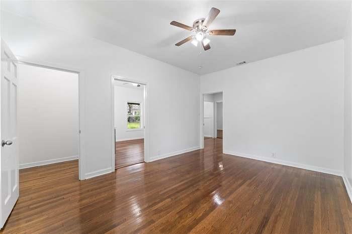 Hardwood flooring throughout, ceiling fan with integrated lighting, white interior doors, and a neutral wall palette