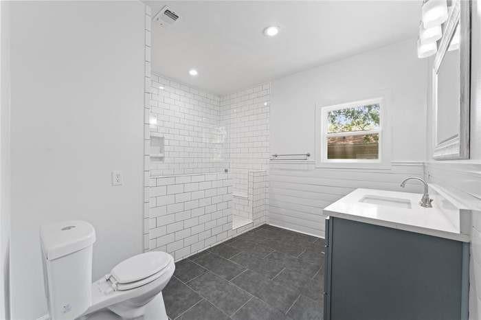 Walk-in shower with subway tile surround, built-in shelving, and glass enclosure