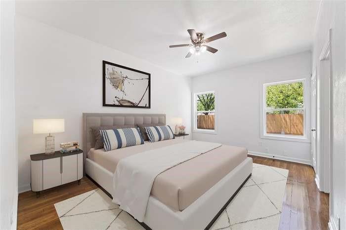 Wood-finish flooring, white walls, two windows, and a ceiling fan with light fixture