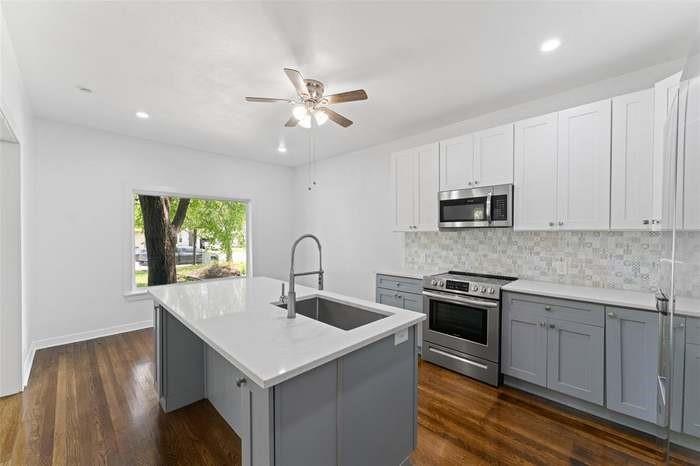 Stainless steel appliances, wood-finish flooring, two-tone cabinetry, a ceiling fan, and recessed lighting Stainless steel appliances, wood-finish flooring, two-tone cabinetry, a ceiling fan, and recessed lighting