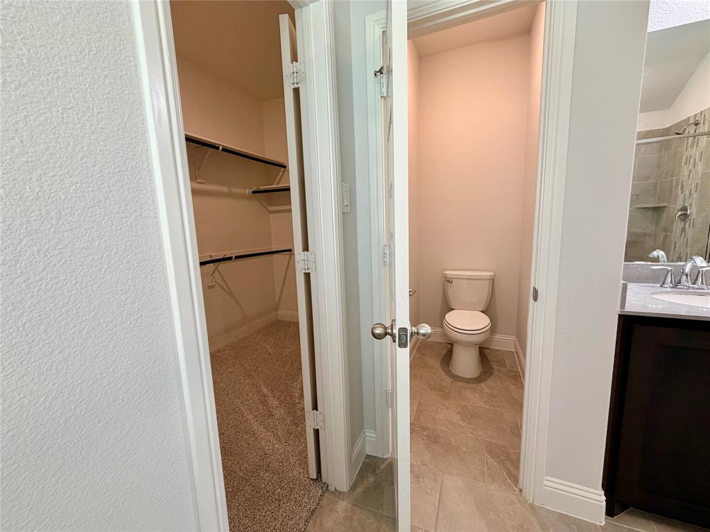 This bathroom features a private, enclosed water closet area that is completely separated from the primary vanity and shower space for enhanced privacy and functionality.
