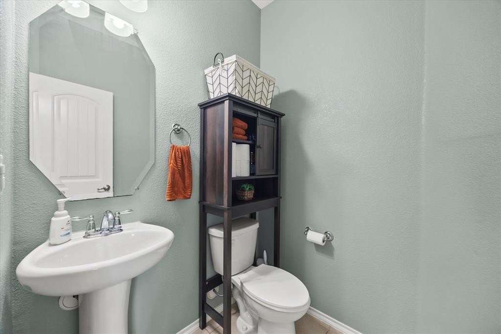 Pedestal sink with chrome faucet, octagonal wall mirror, and built-in over-the-toilet storage cabinet