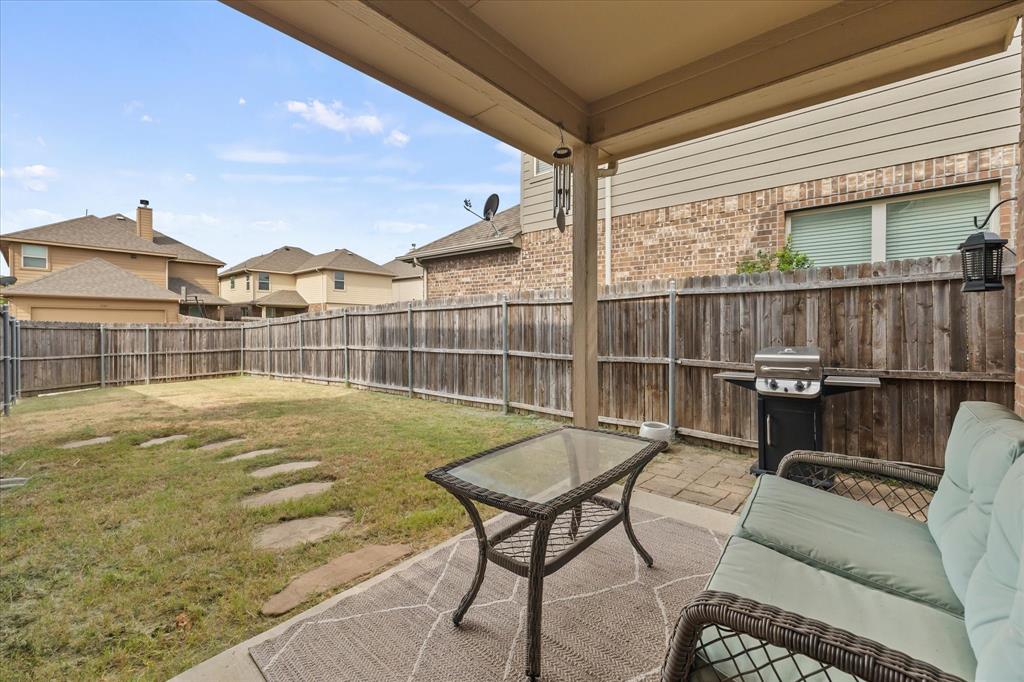 Covered patio with concrete flooring, wood privacy fence, and stepping stone path