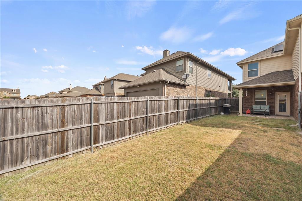 Fenced backyard with a covered patio, brick and siding exterior, and a glass-paneled back door
