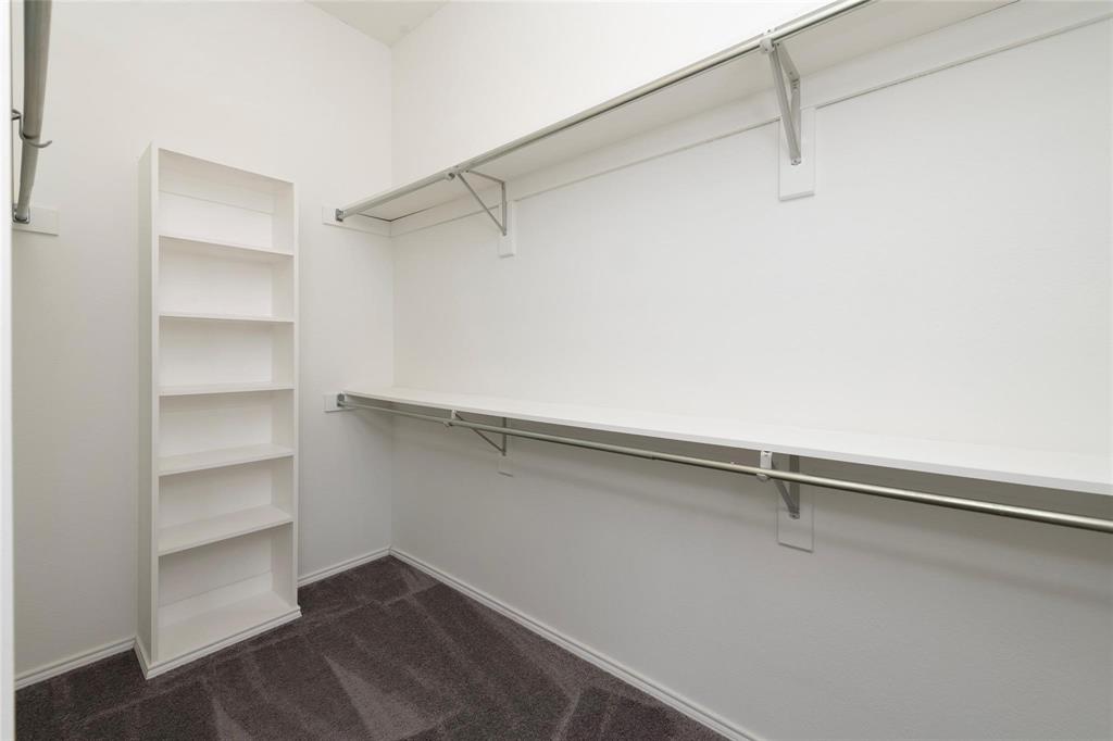 White shelving system, dual hanging rods, upper storage shelf, and carpeted flooring