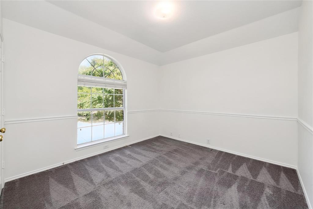 Room featuring an arched window, white walls, and wainscoting