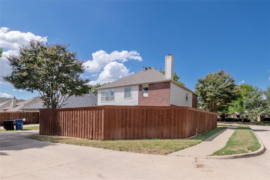 Corner lot property featuring a wood privacy fence, brick and siding exterior, and a visible chimney