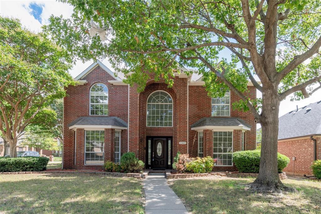 Brick exterior with arched and bay windows, a dark wood-finish entry door, and mature landscaping