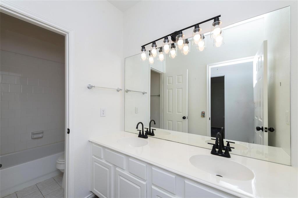 Dual vanity with white cabinetry, integrated sinks, white countertop, and matte black fixtures