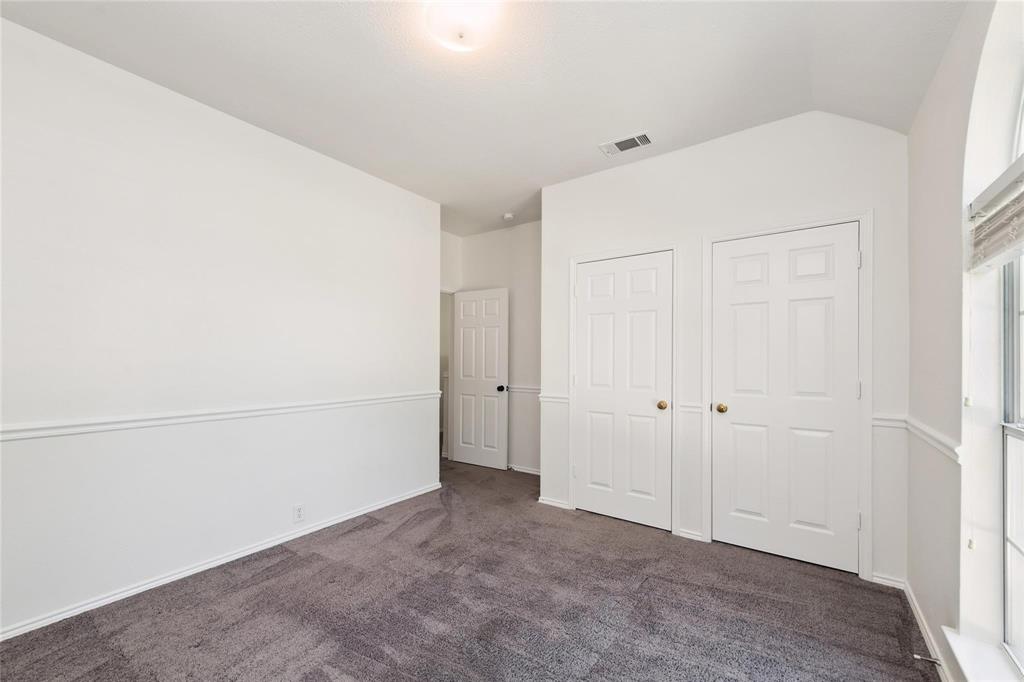 Plush gray carpet flooring, white paneled doors, wainscoting, and an arched window
