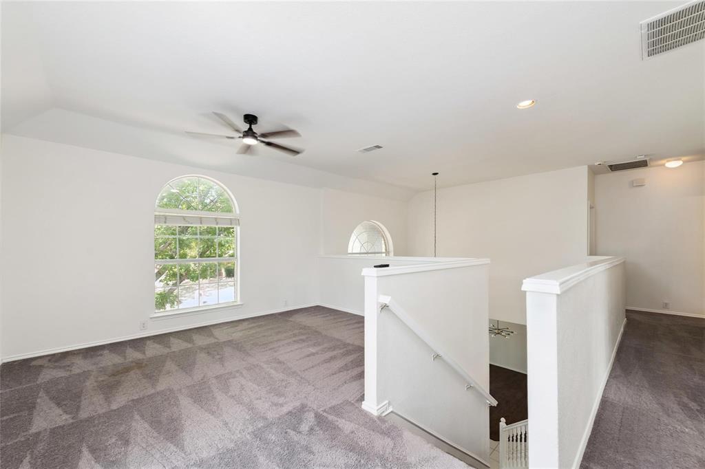 Carpeted loft area featuring an arched window, ceiling fan, recessed lighting, and a white balustrade overlooking a lower level