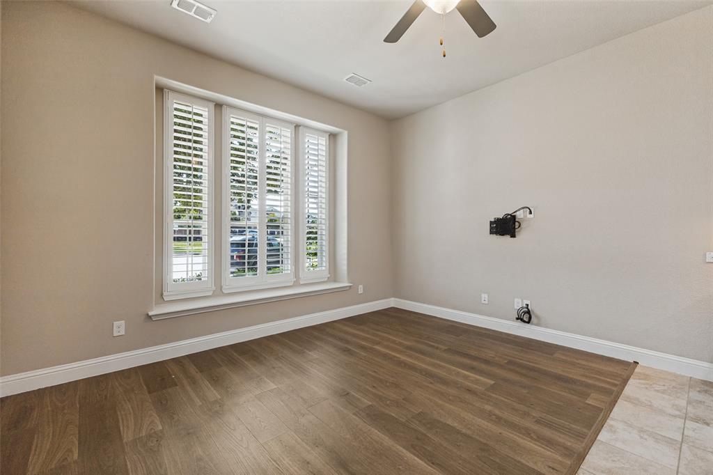 Wood flooring, plantation shutters, ceiling fan, and neutral wall tones