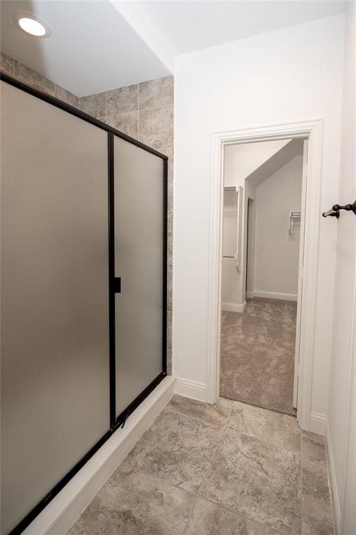 Shower enclosure with frosted glass and black frame, recessed lighting, and tile flooring