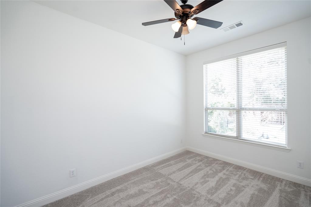 Spacious room with plush carpeting, a large window, a ceiling fan with integrated lighting, and crisp white walls