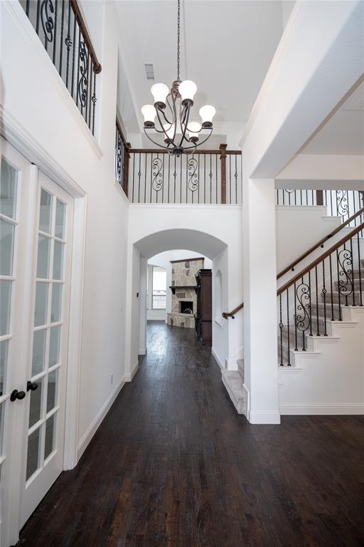 Double-height entryway with wood-finish flooring, an arched doorway, and a chandelier