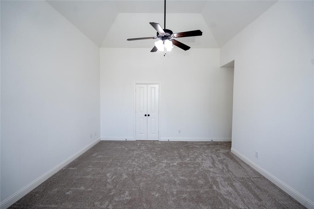 Vaulted ceiling featuring a ceiling fan, neutral carpeting, and white bi-fold doors