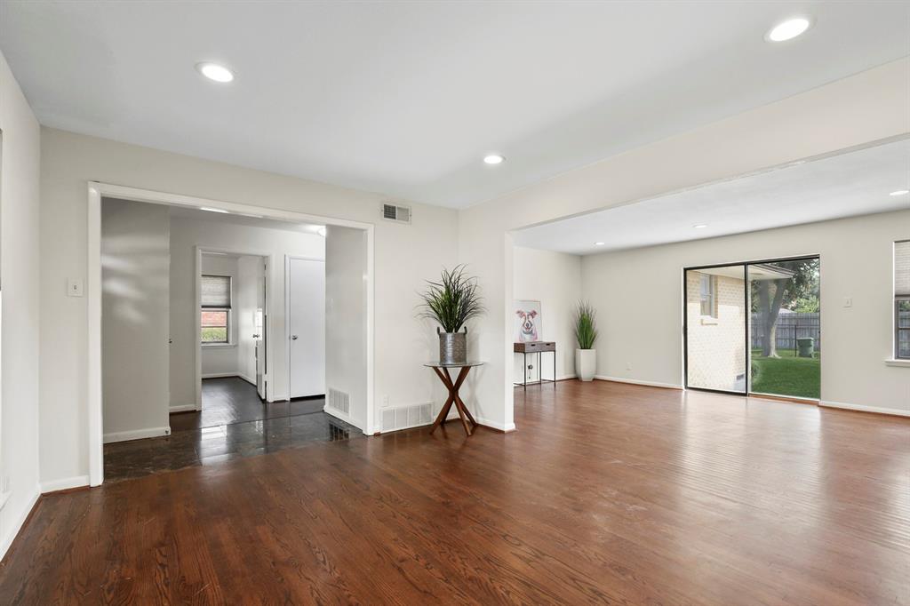 Recessed lighting, dark wood-finish flooring, sliding glass door, white walls, and bright white trim