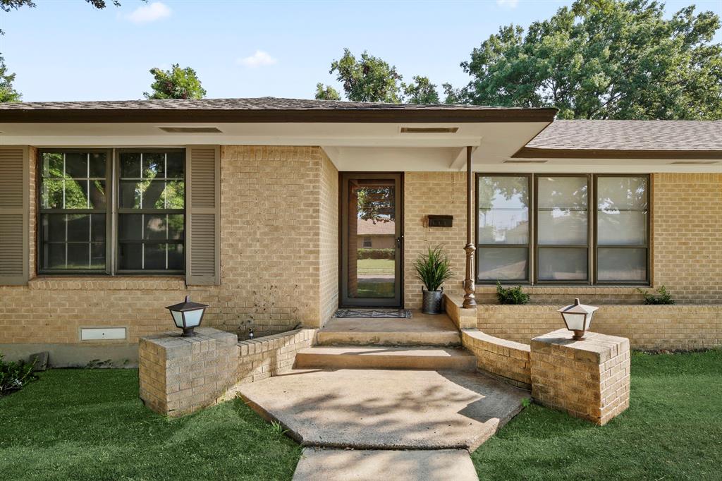Brick exterior featuring brown shutters and an asphalt shingle roof