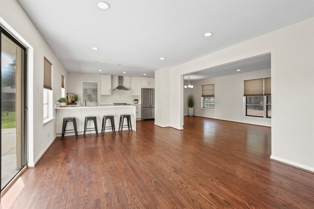 Hardwood flooring throughout, recessed lighting, and a kitchen featuring white cabinetry, stainless steel appliances, and a breakfast bar
