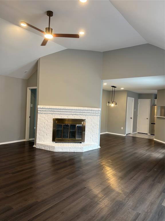 Vaulted ceiling with a ceiling fan, fireplace with a white brick surround, wood-finish flooring, and recessed lighting Vaulted ceiling with a ceiling fan, fireplace with a white brick surround, wood-finish flooring, and recessed lighting