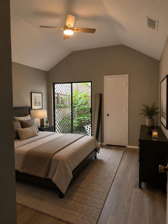 Vaulted ceiling with an attached ceiling fan, large glass sliding door, and wood-finish flooring