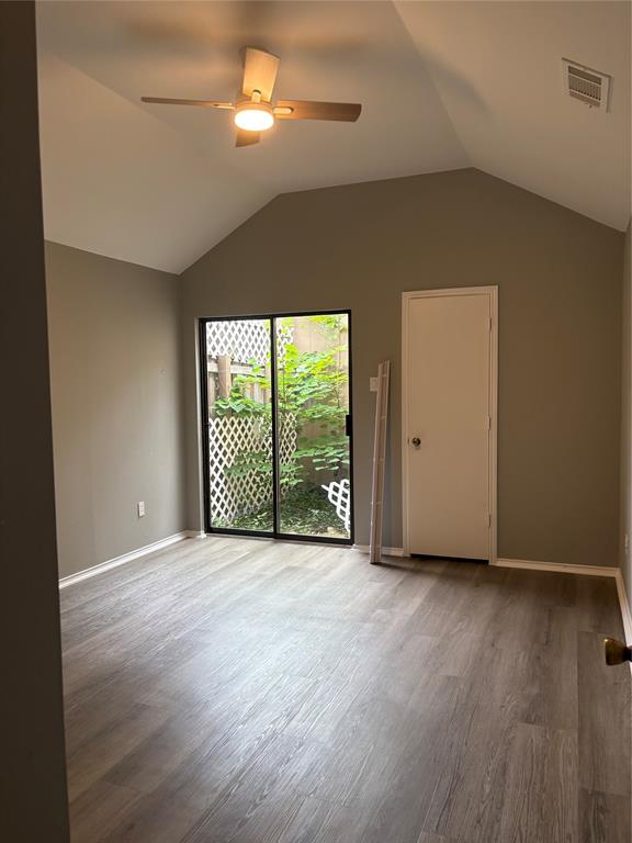 Vaulted ceiling, wood-finish flooring, ceiling fan with integrated lighting, sliding glass door, and a private patio with lattice fencing Vaulted ceiling, wood-finish flooring, ceiling fan with integrated lighting, sliding glass door, and a private patio with lattice fencing