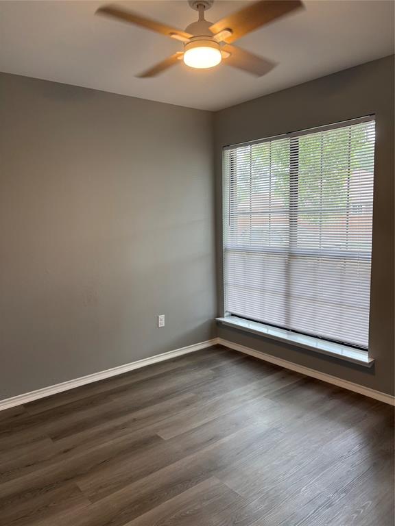 Wood-finish flooring, neutral wall tones, window with horizontal blinds, and a ceiling fan with integrated lighting