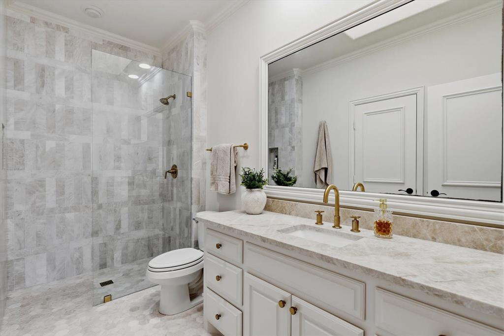 Marble tile, quartzite surfaces and polished brass fixtures elevate this remodeled ensuite bath.
