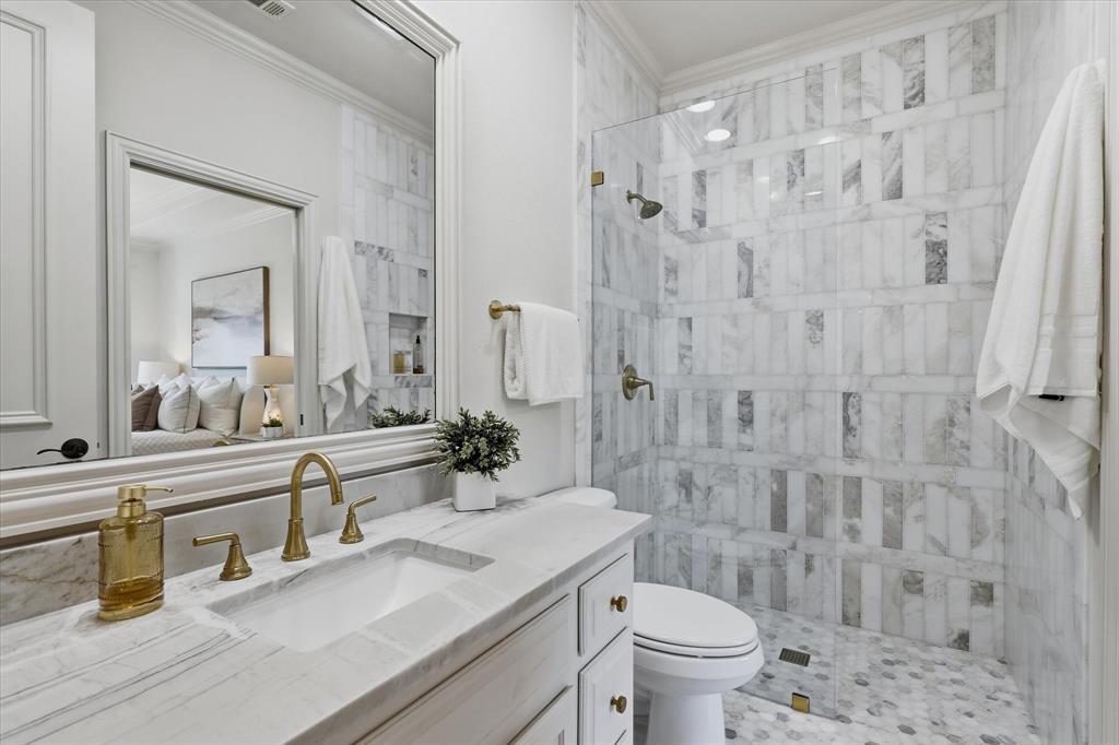 The updated ensuite bath features marble finishes, a glass-enclosed shower and elegant brass fixtures.