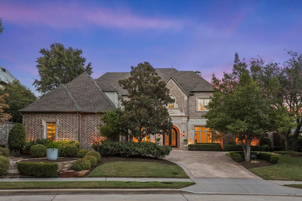 Twilight view of the timeless brick-and-stone exterior, mature trees and welcoming arched entry with custom double iron door surrounded by detailed cast stone. Twilight view of the timeless brick-and-stone exterior, mature trees and welcoming arched entry with custom double iron door surrounded by detailed cast stone.