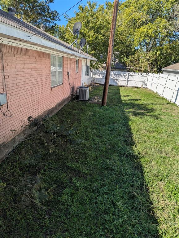Fenced backyard with a grassy lawn and mature shade trees, offering outdoor space with plenty of potential for landscaping, gardening, or creating your own backyard retreat!